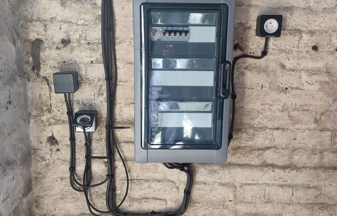 Coffret et cheminements posés sur un mur de pierre du bâti local
